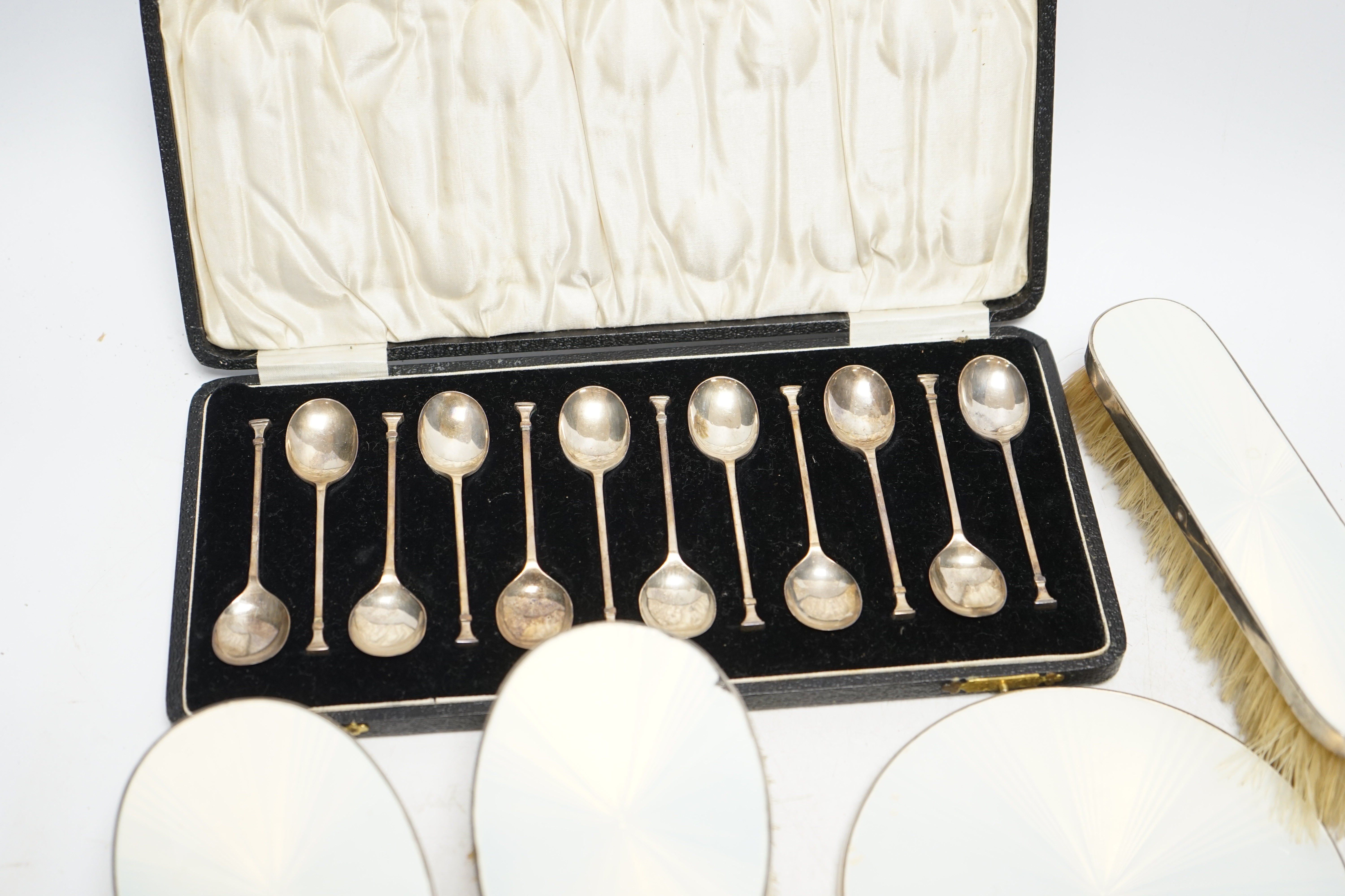 A cased set of twelve George V silver teaspoons, William Suckling Ltd, Birmingham, 1928, 90mm, together with a 1930's silver and enamel mounted for piece mirror and brush set. Condition - poor